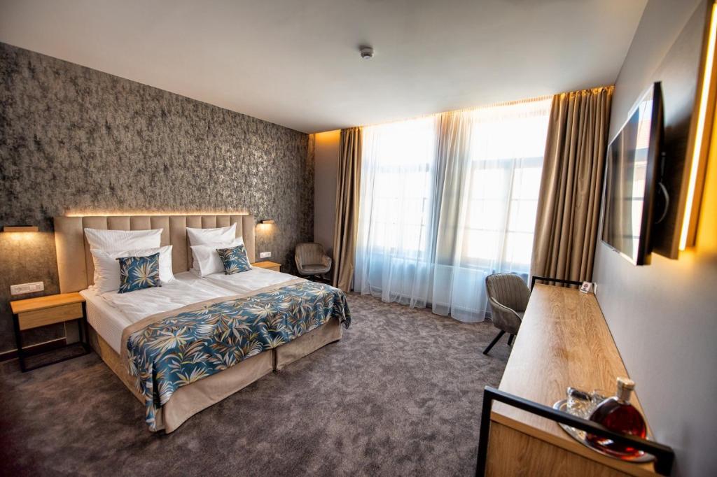 Cette chambre comprend un lit et une grande fenêtre. dans l'établissement JOYME Hotel, à Sibiu