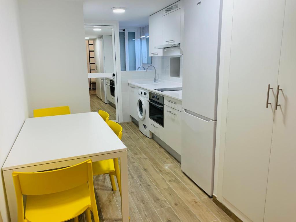 una cocina con sillas amarillas y una mesa blanca en Piso céntrico y funcional, en Madrid