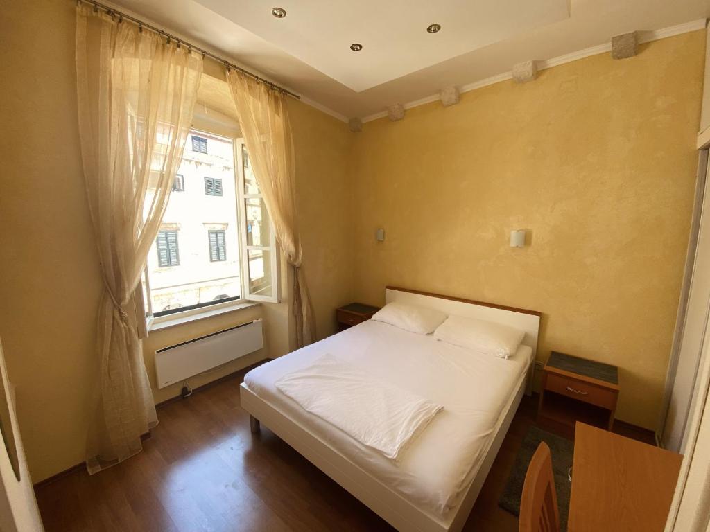 a small bedroom with a bed and a window at Apartment Tomasović Old Town in Dubrovnik