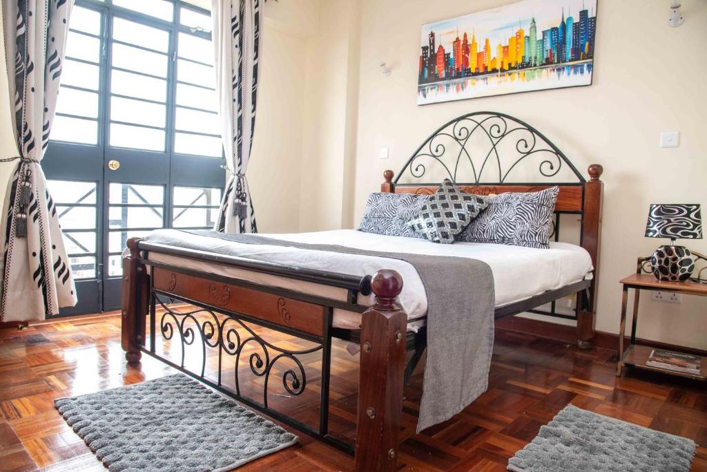 a bedroom with a large bed with a wooden floor at Westlands place 1 bedroom - Safari House, Sherry Homes in Nairobi