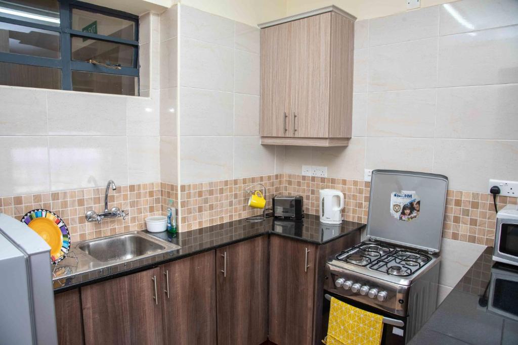 a small kitchen with a stove and a sink at Westlands place 1 bedroom - Safari House, Sherry Homes in Nairobi