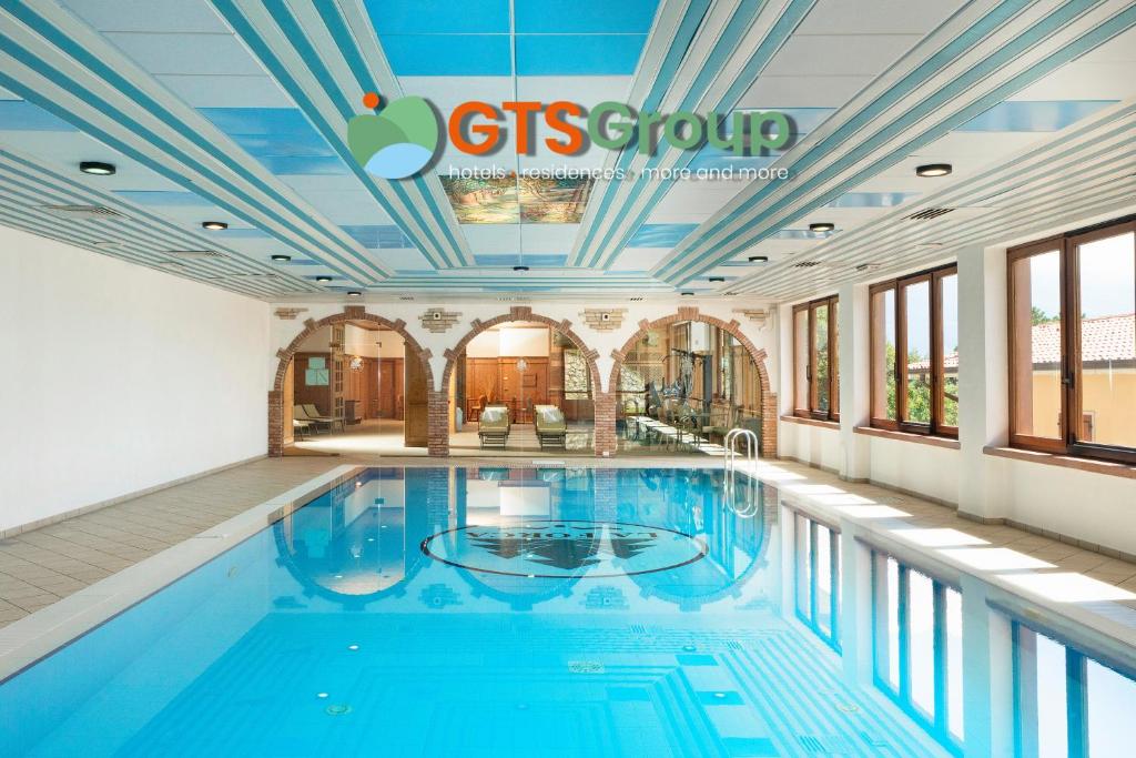- une grande piscine d'eau bleue dans un bâtiment dans l'établissement Hotel Residence Panorama La Forca, GTSGroup, à Tignale