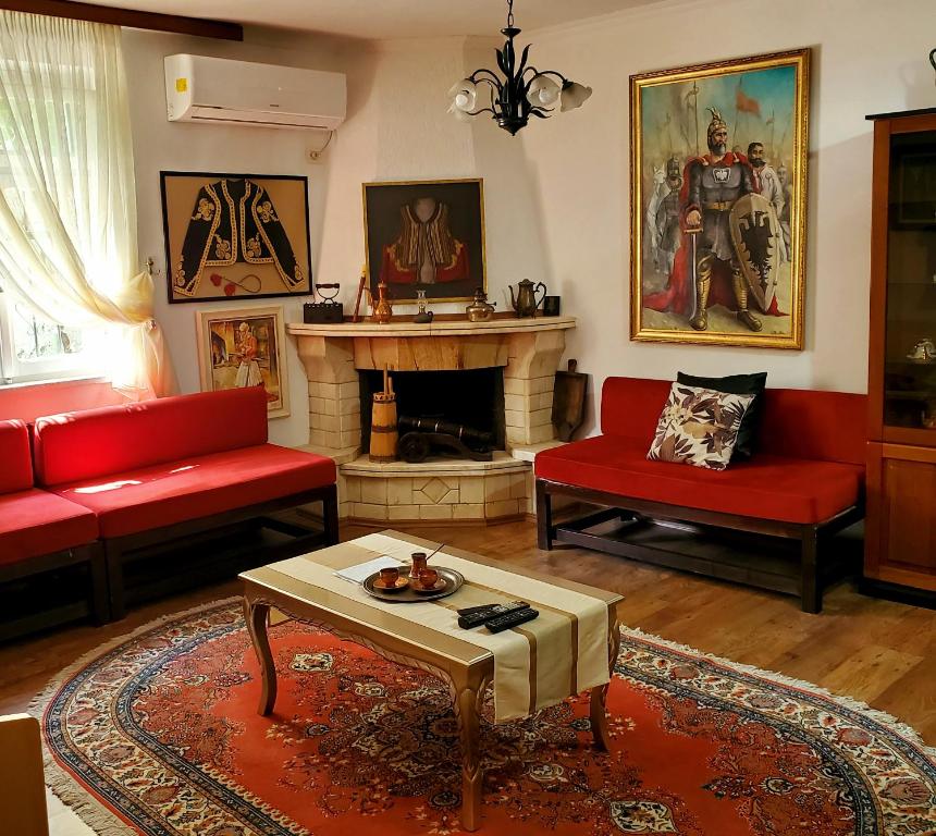 a living room with a red couch and a fireplace at Unique Traditional House, hosted by J&G in Tirana