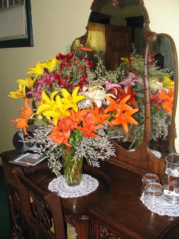 a vase of flowers on a table in front of a mirror at Heartwood Inn in Drumheller