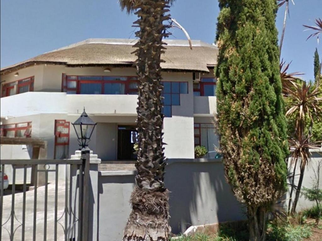 a house with two palm trees in front of it at Melted Butter Lodge in Bayswater