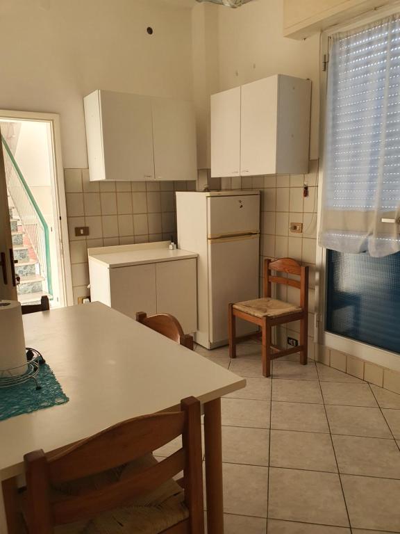 里米尼的住宿－Appartamento Viserba，厨房配有白色橱柜和桌椅