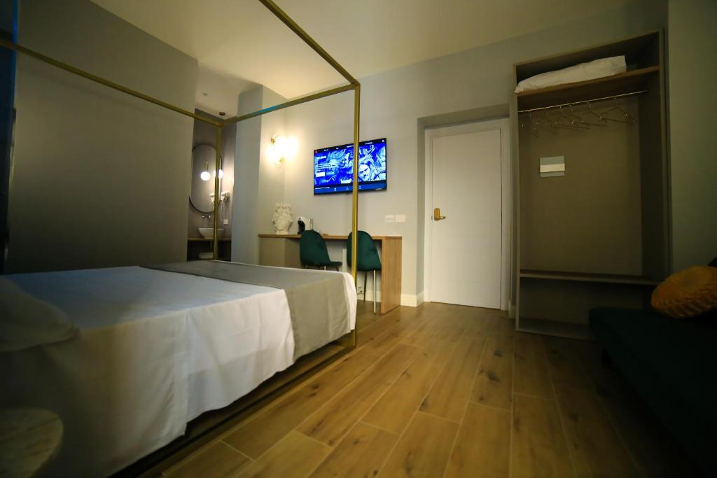 a bedroom with a white bed and a tv on the wall at Krysos Luxury Rooms in Agrigento