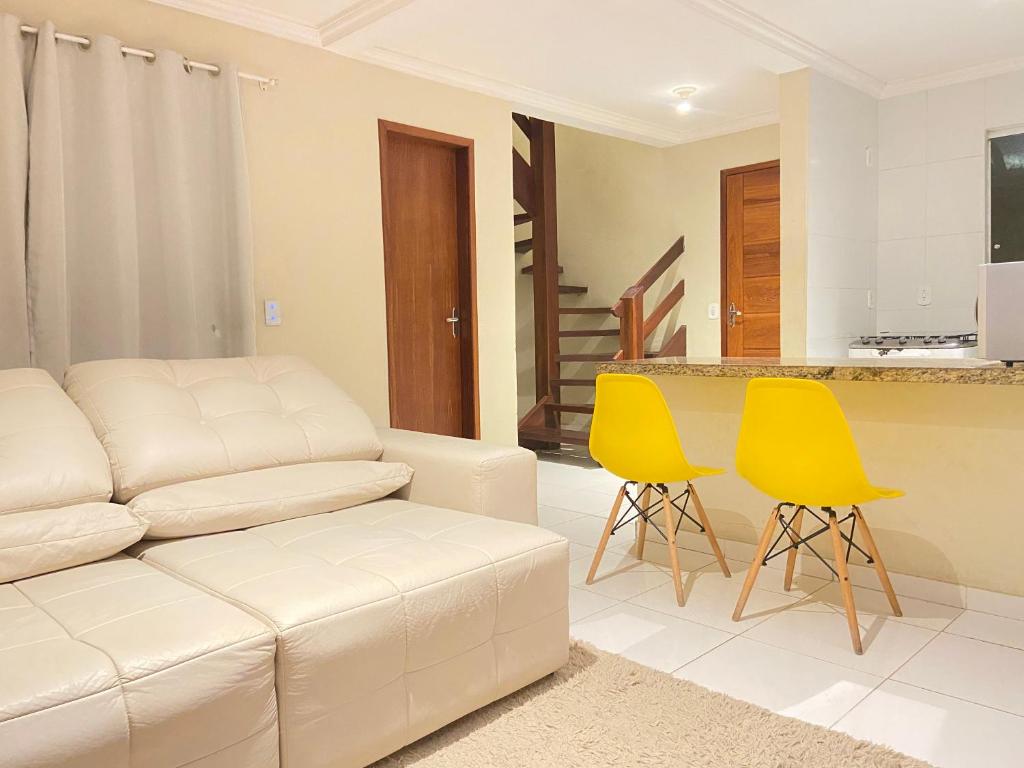 sala de estar con sofá blanco y 2 sillas amarillas en Casa Kiwi - Aluguel Temporada, en Porto Seguro