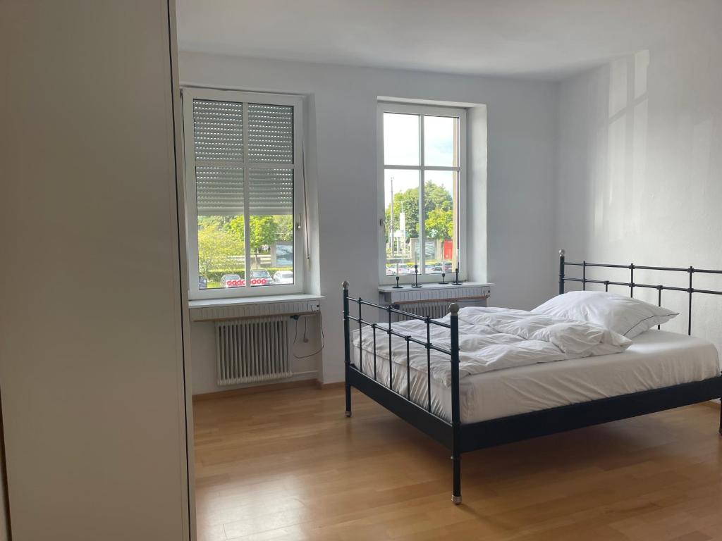 a bedroom with a bed and two windows at Apartments am Bodensee in Bregenz