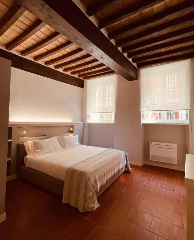 een slaapkamer met een groot bed en twee ramen bij Palazzo Borgocolonne Apartments in Parma