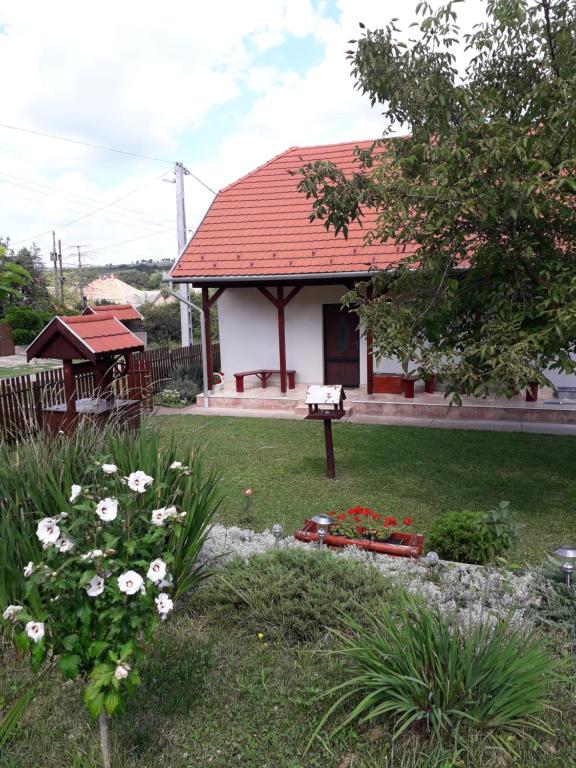 ein Haus mit rotem Dach und einem Garten mit Blumen in der Unterkunft Mátyásmadár Vendégház in Tard