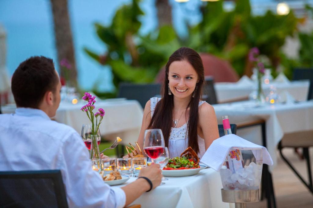 a man and woman sitting at a table with a glass of wine at Queens Bay Hotel in Paphos
