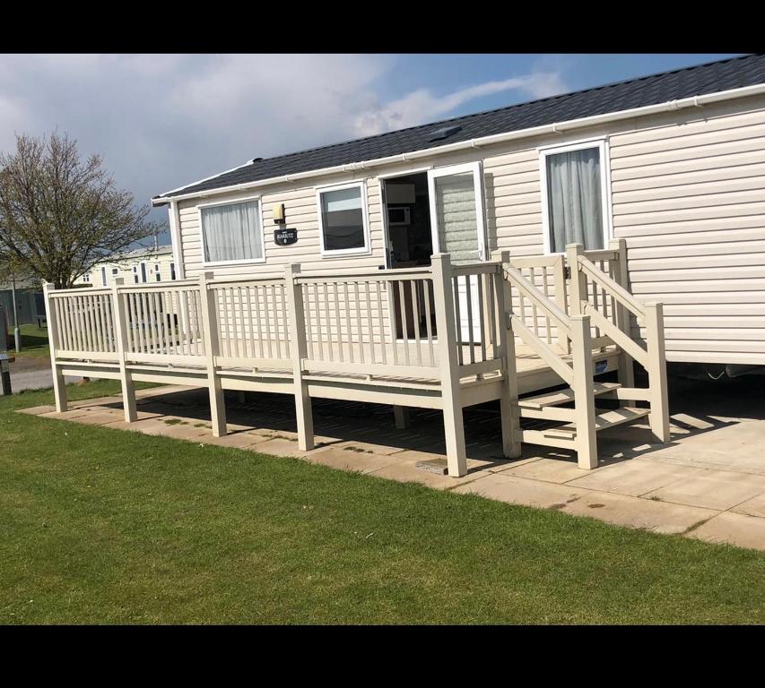 a white house with a porch and a wooden deck at 8 Berth,Waterside Leisure,Ingoldmells in Ingoldmells