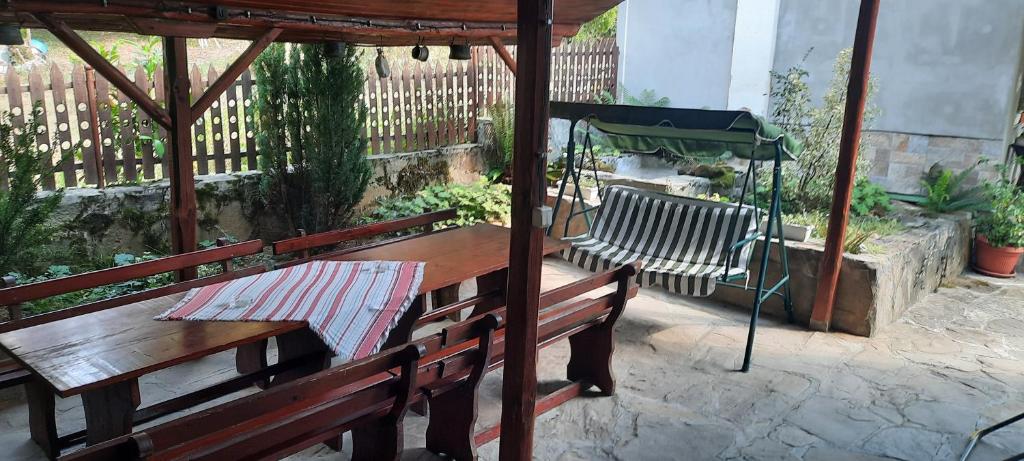 una mesa de madera y un banco bajo un cenador en Guest House Lazar Raykov en Ribarica