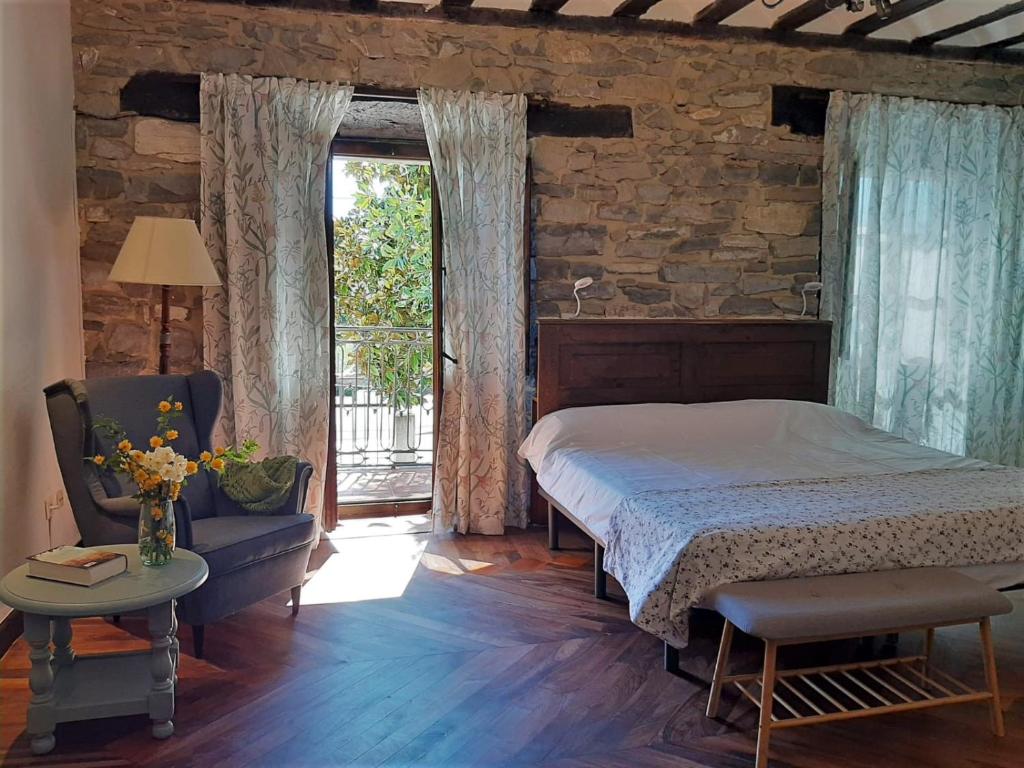 a bedroom with a bed and a chair and a window at Hotel Doña Lola in Izarra