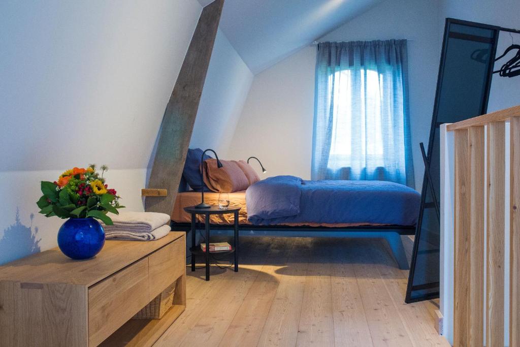 Un dormitorio con una cama y una mesa con un jarrón de flores en Maisonnette FREA, en Rozebeke