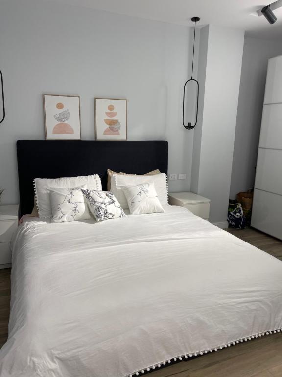 a white bed with white sheets and pillows at بنتهاوس ميدتاون ممنوع الزيارات للعزاب in Cairo