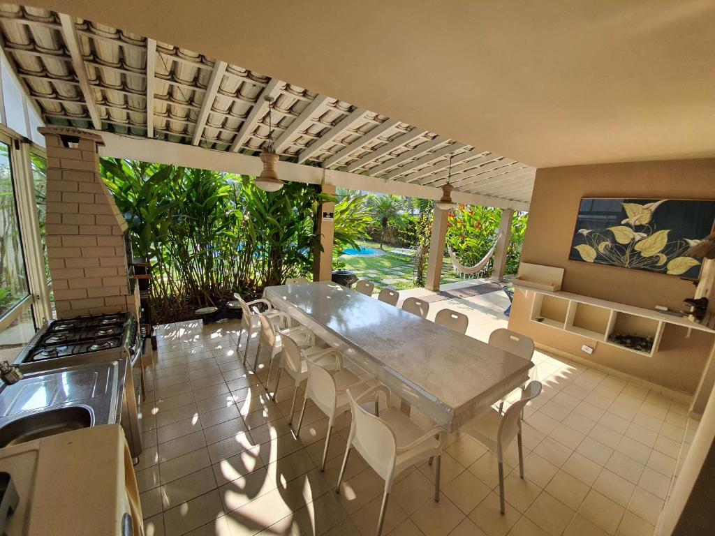 ein Esszimmer mit einem Tisch und weißen Stühlen in der Unterkunft Casa com seis suites, Praia de Pernambuco Guarujá in Guarujá