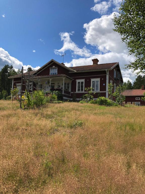 una casa en una colina con un campo delante en Långhedgården Bed & Breakfast en Alfta