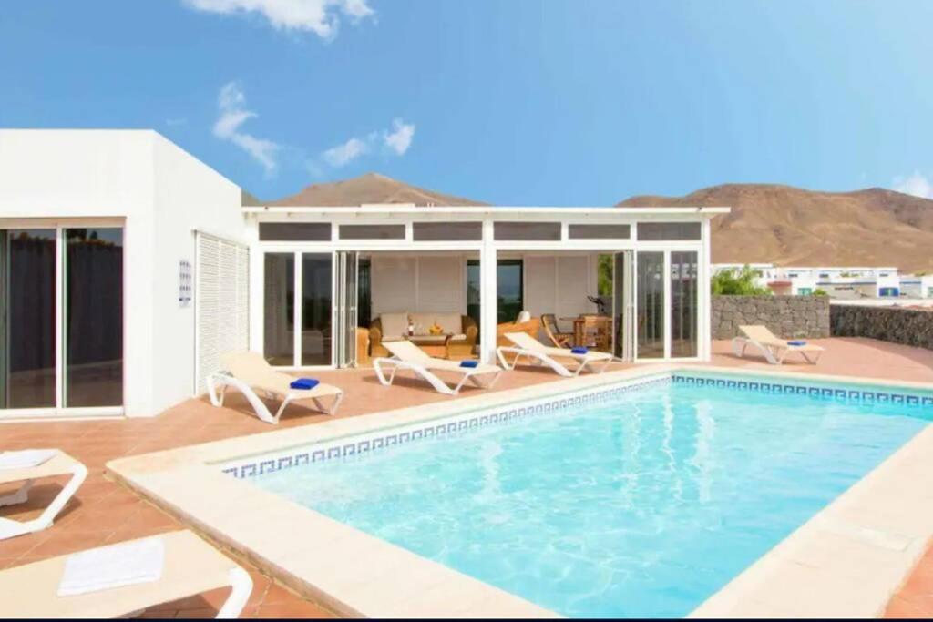 uma piscina com cadeiras e uma casa em Villa Papagayo Relax em Playa Blanca