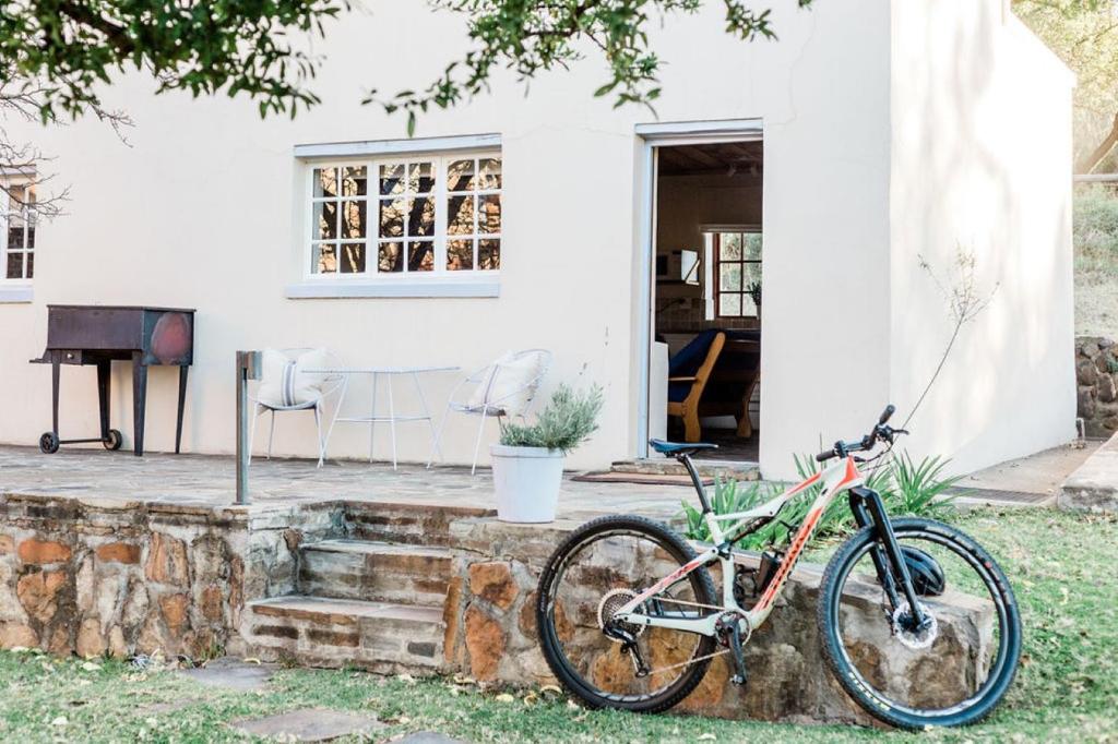 a bike parked on a stone wall in front of a house at Onbedacht Cottage in Graaff-Reinet