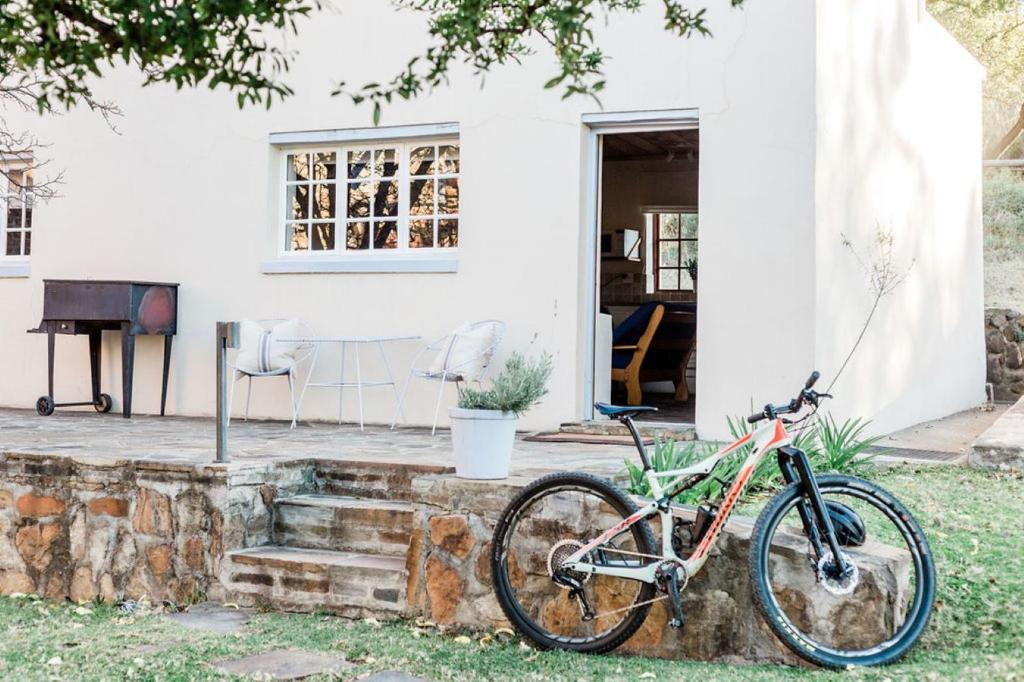 una bicicletta parcheggiata su un muro di pietra di fronte a una casa di Onbedacht Cottage a Graaff-Reinet