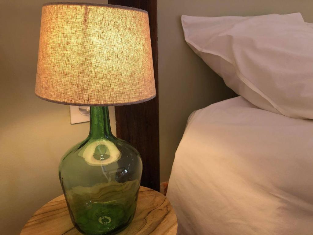 a green glass lamp sitting on a table next to a bed at L'ancienne Forge in Allemant