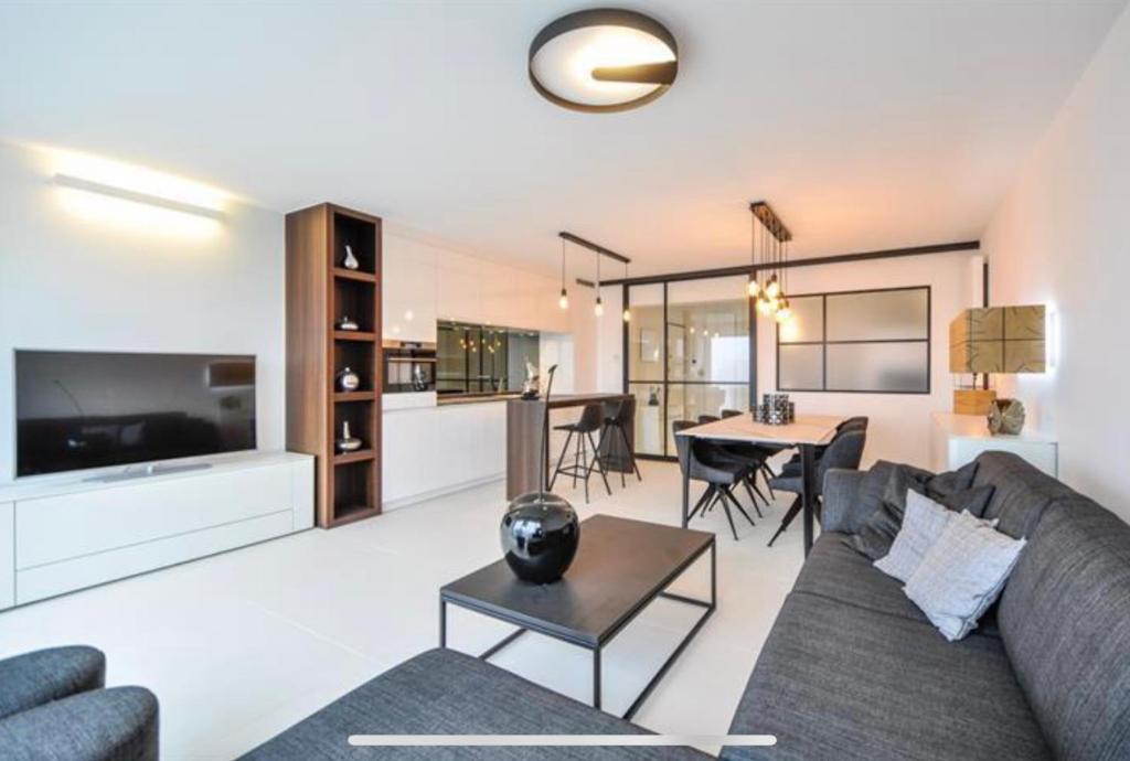 een woonkamer met een bank en een tafel bij Luxe appartement Arte, 50m van het Zoute strand in Knokke-Heist