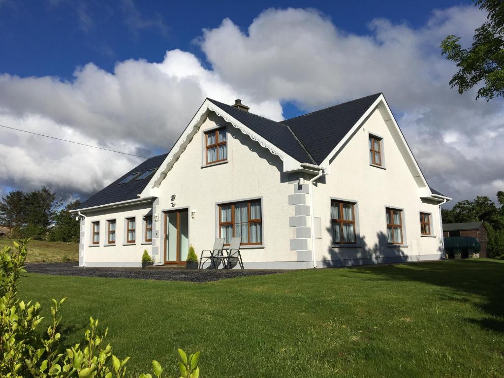 a white house with a black roof on a yard at Milltown Lough Eske Bed & Breakfast in Ardeevin