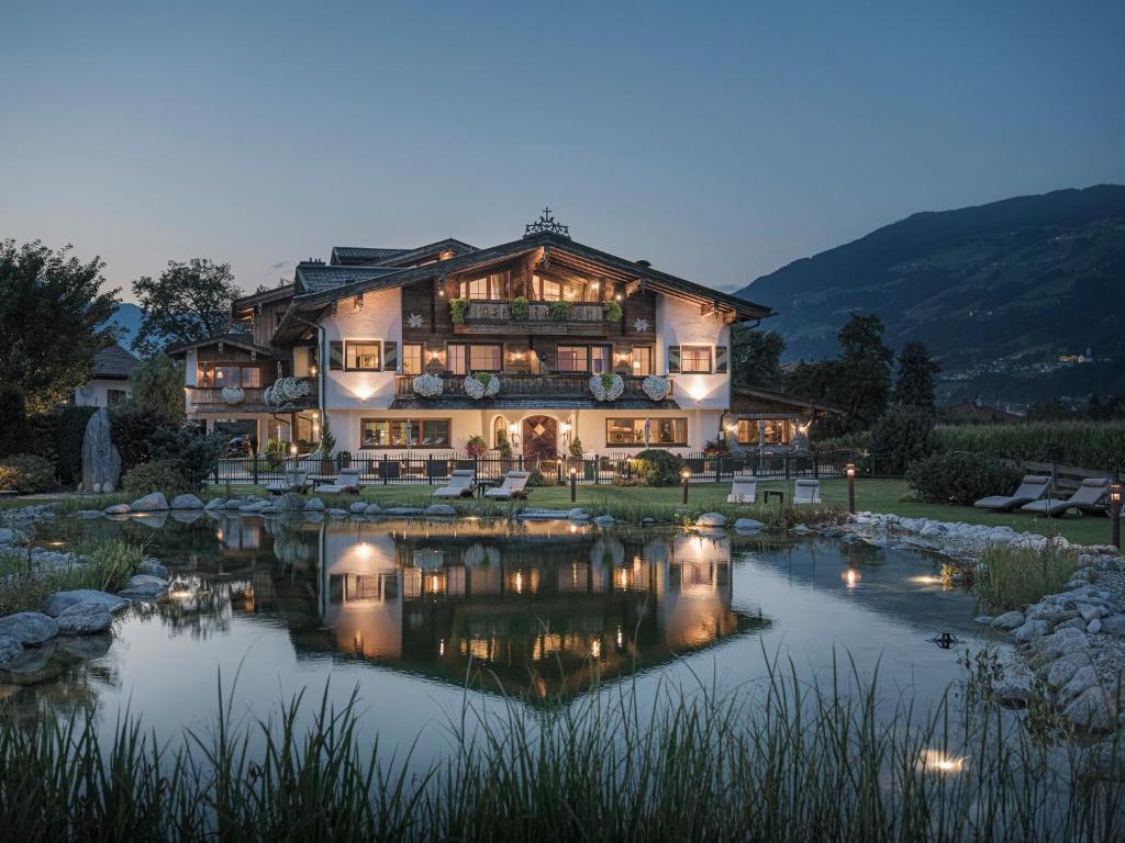 a large house with a pond in front of it at Aparthotel Stacherhof in Fügen