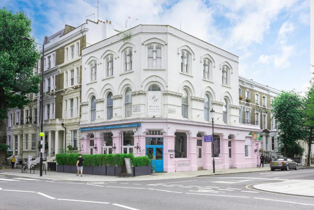 ein rosa und weißes Gebäude in einer Stadtstraße in der Unterkunft Notting Hill Hotel by CAPITAL in London