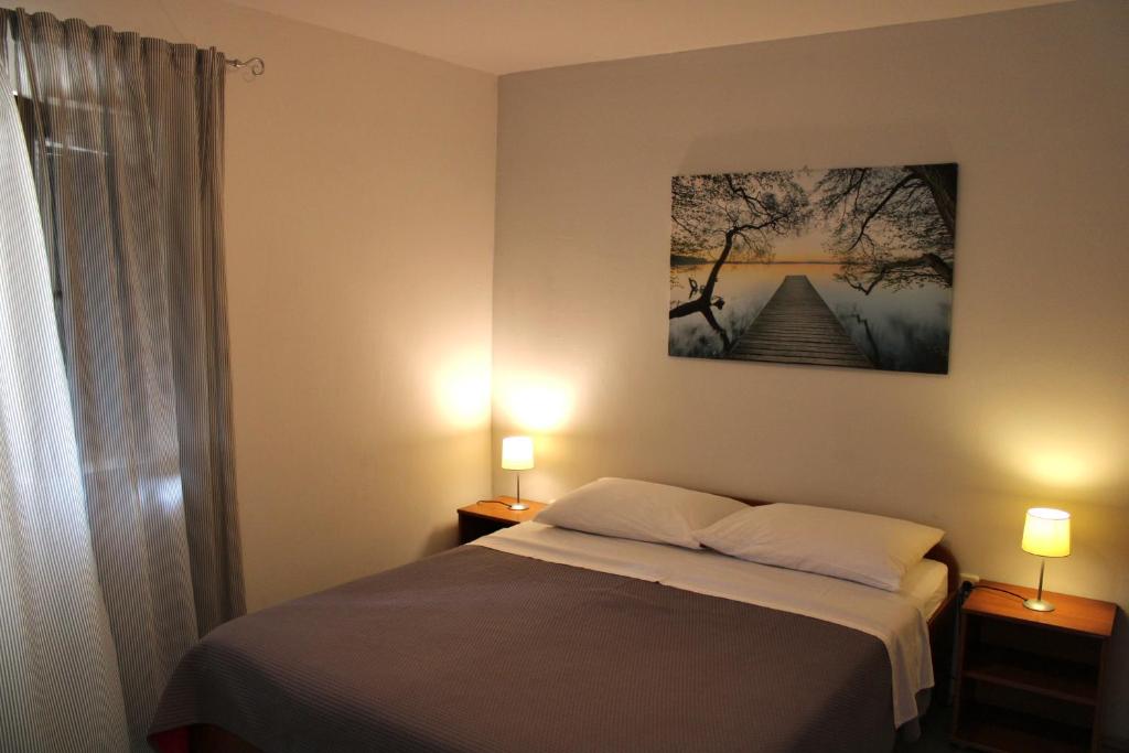 um quarto com uma cama e dois candeeiros e uma imagem na parede em Apartmani Tina Pakoštane em Pakoštane