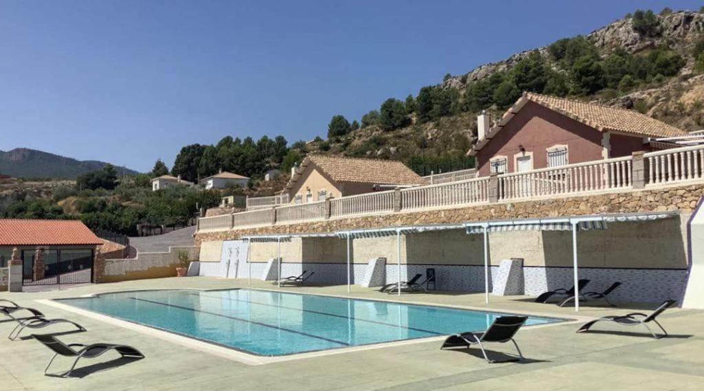 a large swimming pool with chairs and a house at Finca La Ecarada. Férez (Albacete) in Férez