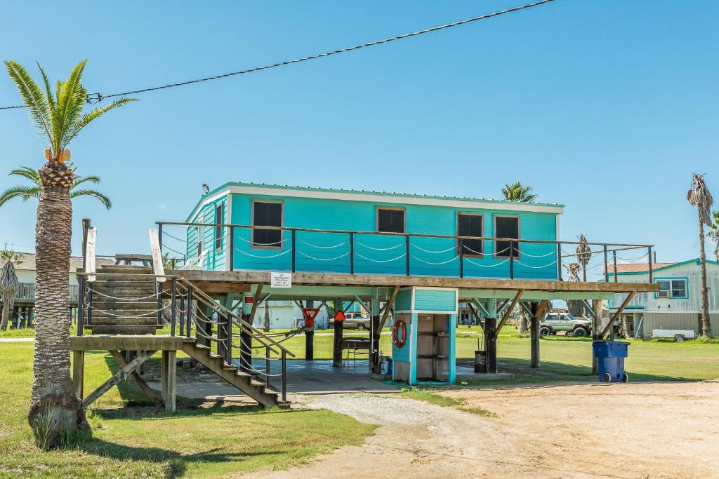 uma casa sobre uma estrutura de madeira com uma palmeira em Surfside Serenity em Surfside Beach