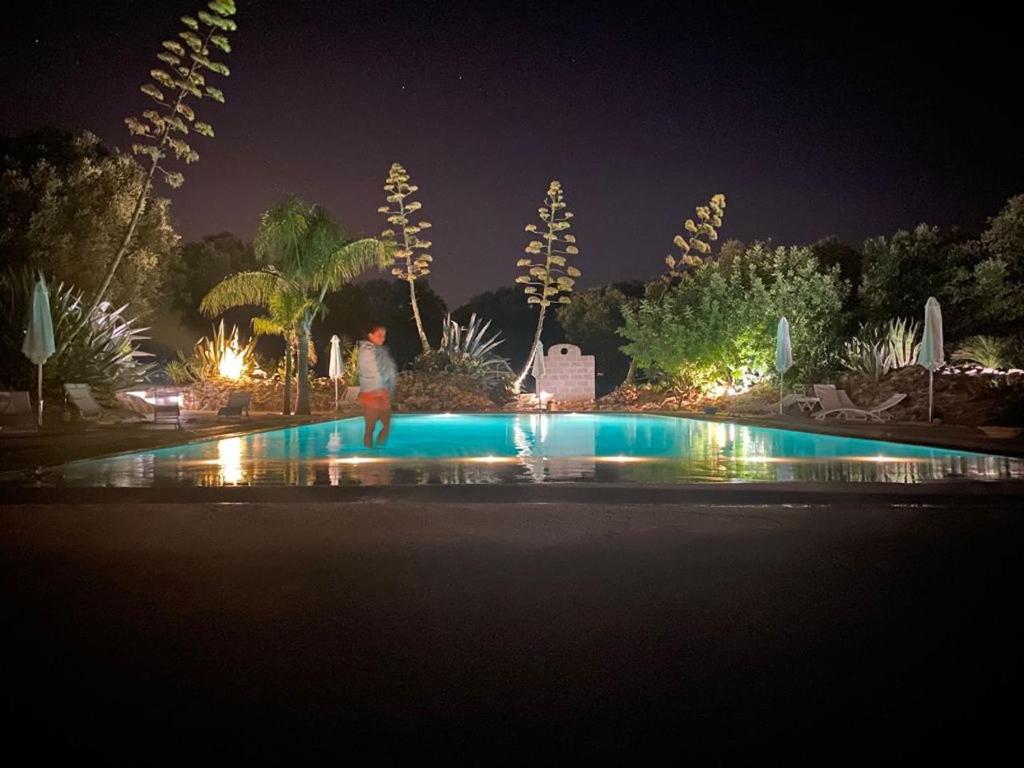 uma pessoa ao lado de uma piscina à noite em La Monacedda - Country Boutique Apartments - Villa Laura Ostuni em Ostuni