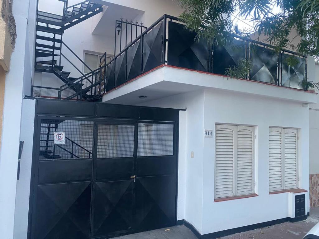 a white house with a black garage door and stairs at Hermoso departamento, excelente ubicación in San Fernando del Valle de Catamarca