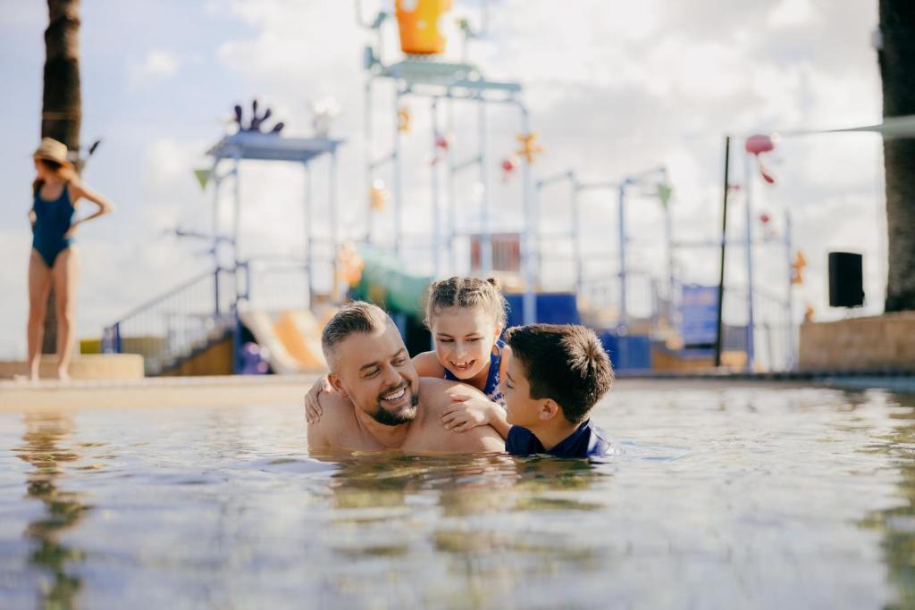 Ein Mann und zwei Jungs im Schwimmbad. in der Unterkunft Sea World Resort in Gold Coast