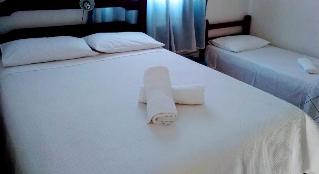 a white bed with a rolled up towel on it at Bnb Silvia Home in Rio de Janeiro