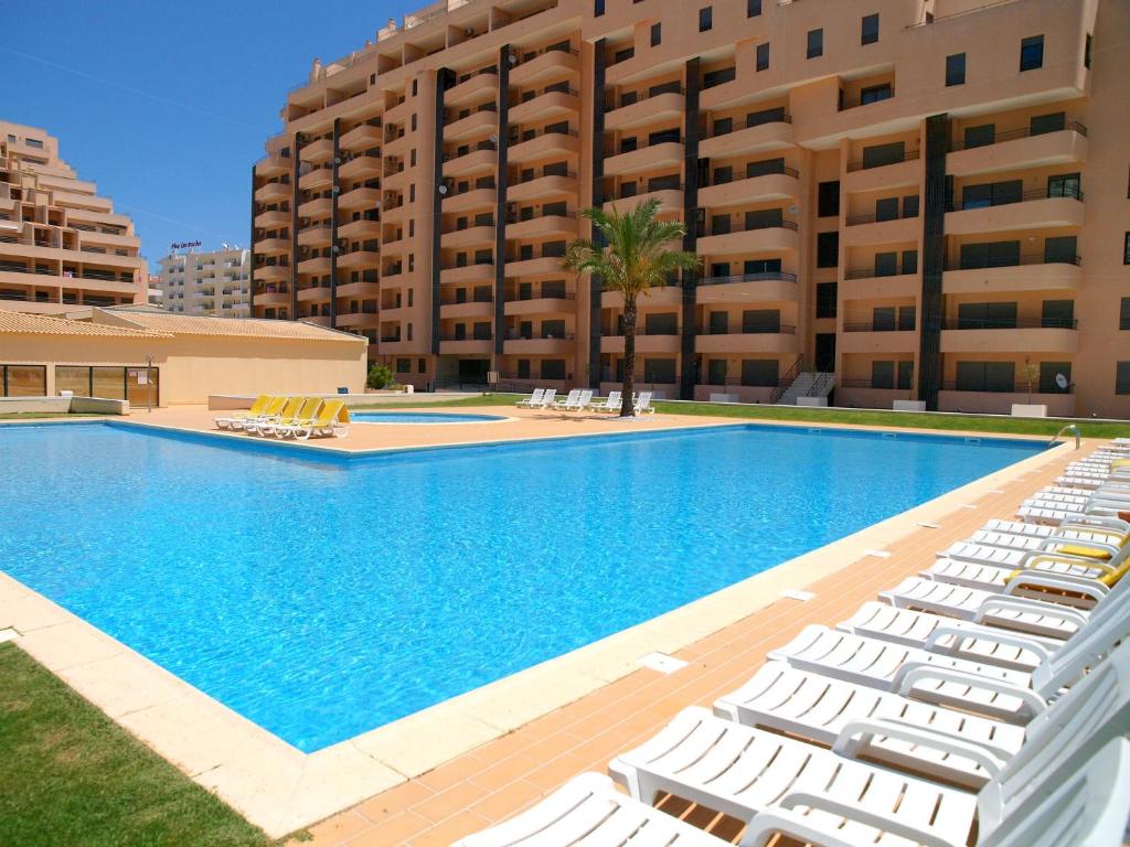 a swimming pool with lounge chairs in front of a building at Apartamentos Paraíso Sol da Rocha in Portimão