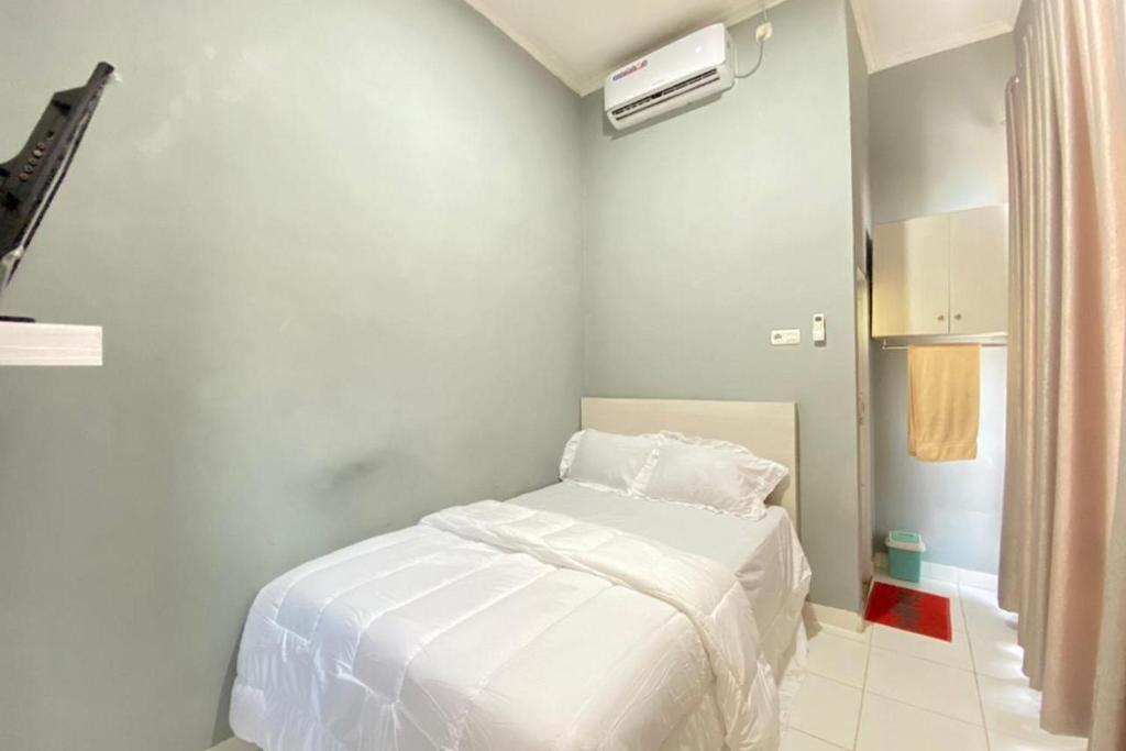 a white bedroom with a bed in a room at Pelangi Guest House Palembang RedPartner in Talang Kelapa