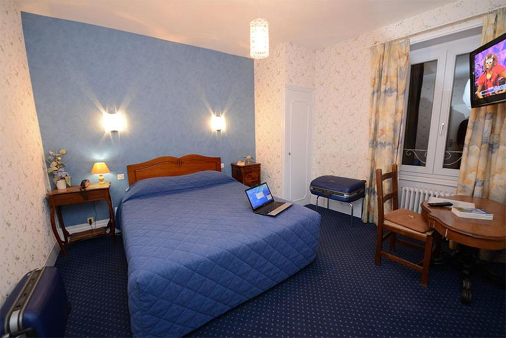 a hotel room with a bed with a laptop on it at Hôtel De La Ferté in Chagny