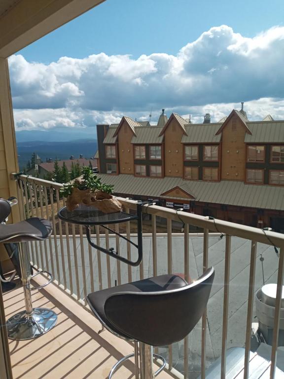a balcony with chairs and a table on a deck at Village Center 2 bedroom Condo in Big White