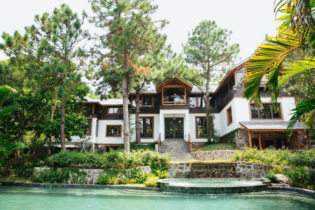 une maison avec un étang en face de celle-ci dans l'établissement AMAYA HOME - Lodge, Spa & Restaurant, à Hanoï