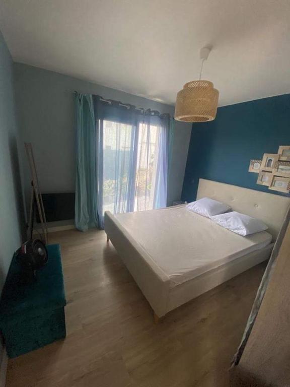 - une chambre avec un lit blanc et un mur bleu dans l'établissement Maison cosy au calme, à La Colle-sur-Loup