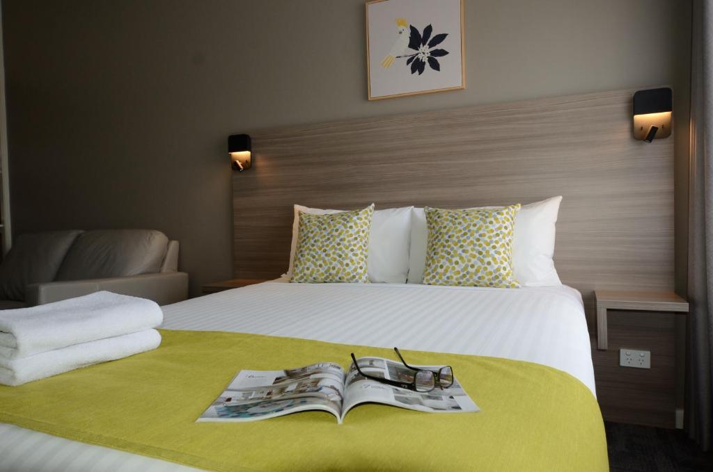 a hotel room with a bed with a book on it at 105 On The Park in Bordertown