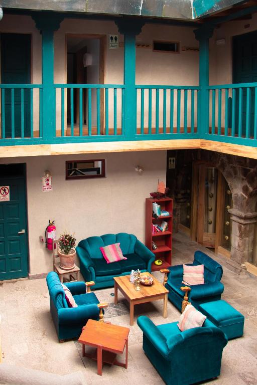 un soggiorno con divani blu e tavoli di fronte a un edificio di Nao Victoria Hostel a Cuzco