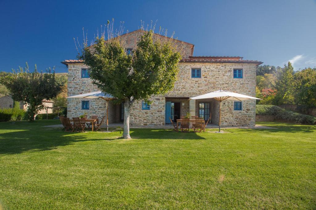 una gran casa de piedra con un árbol en el patio en Odina Agriturismo, en Loro Ciuffenna