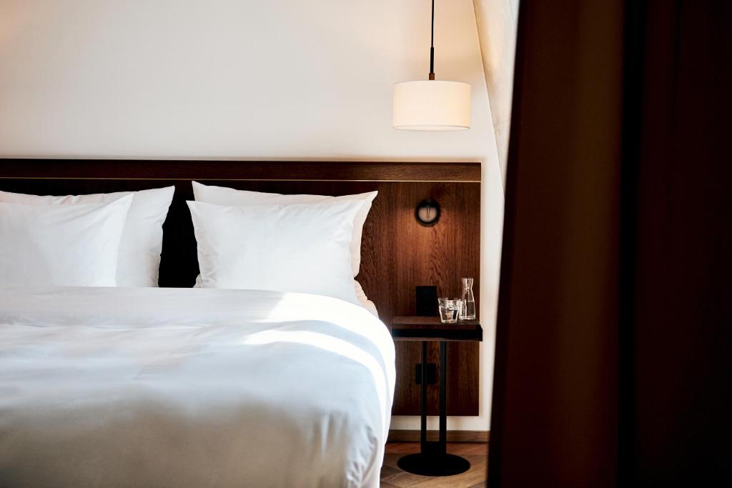 a bedroom with a white bed and a night stand at Karl August - a Neighborhood Hotel in Nuremberg