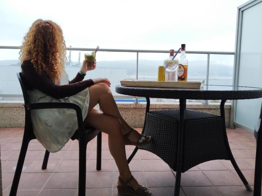 a woman sitting at a table with a drink at Moments Romantiques in Pontevedra