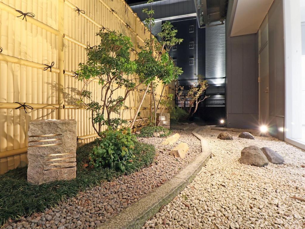 a garden with a tree in front of a building at CHISUN BUDGET Kanazawa Ekimae in Kanazawa